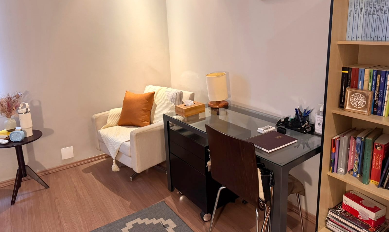 Mesa de trabalho e estante com as obras de Freud no consultório
